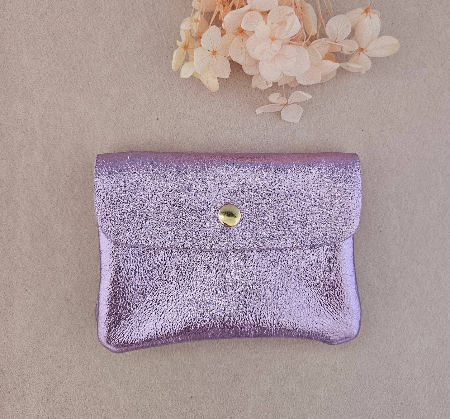 Portemonnaie aus upgecyceltem Leder in der Farbe flieder metallic mit Druckknopf und innenliegendem Reißverschlussfach.
