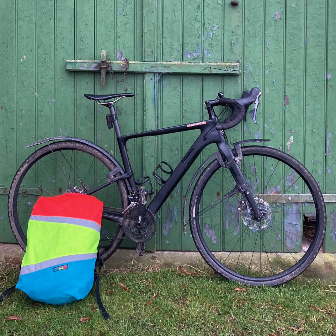 bunter Rucksacküberzug mit Reflexstreifen an Rennrad gelehnt