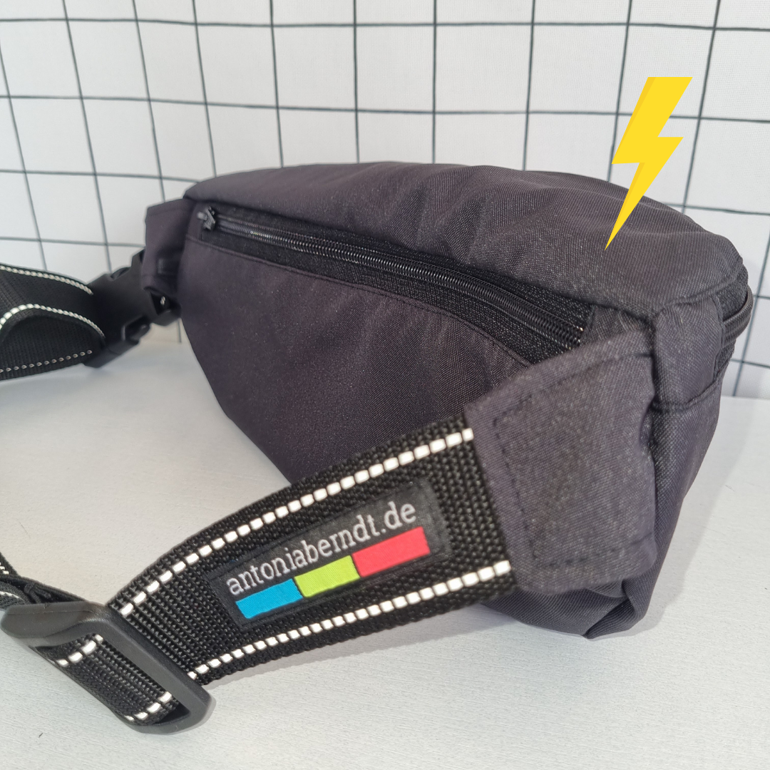 Crossbag in schwarz mit Reflexstreifen im Schultergurt.