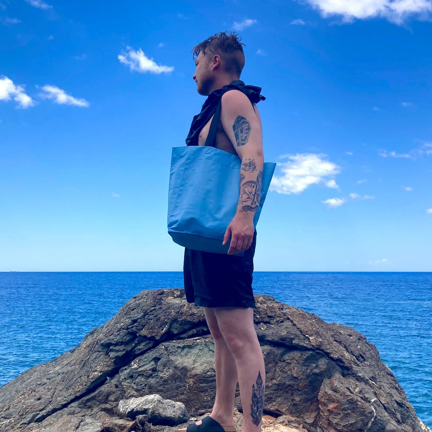 Mann mit bikesac simply blue cobag Tasche auf Felsen vor Meer