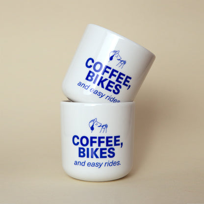 zwei aufeinandergestapelte Tassen mit blauem aufdruck: "Coffee, Bikes and easy rides"