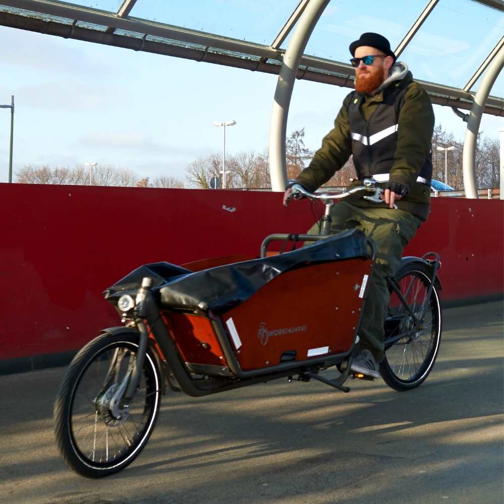 Lastenradfahrer mit schwarzer Warnweste auf Fahrrad