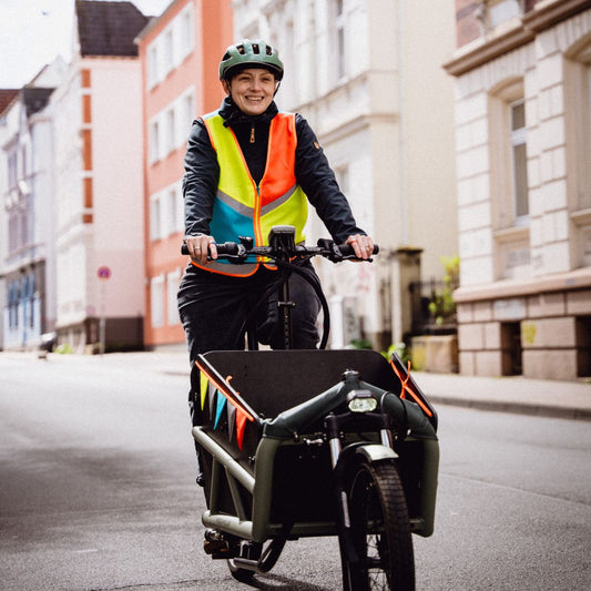 Lastenradfahrerin mit bunter Warnweste von antoniaberndt