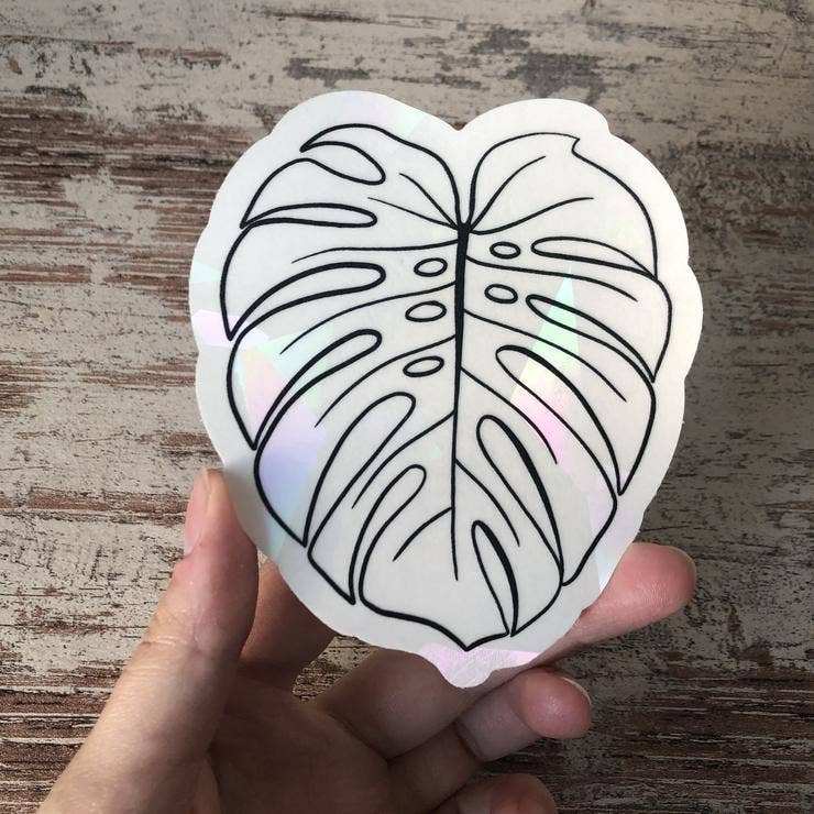 Suncatcher Sticker Monstera von Plantyintroverts mit Folie in Hand.