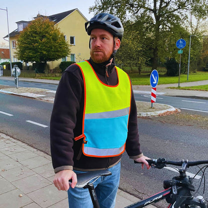 Überwurf in neongelb und blau mit Reflexstreifen angezogen von einem Fahrradfahrer.